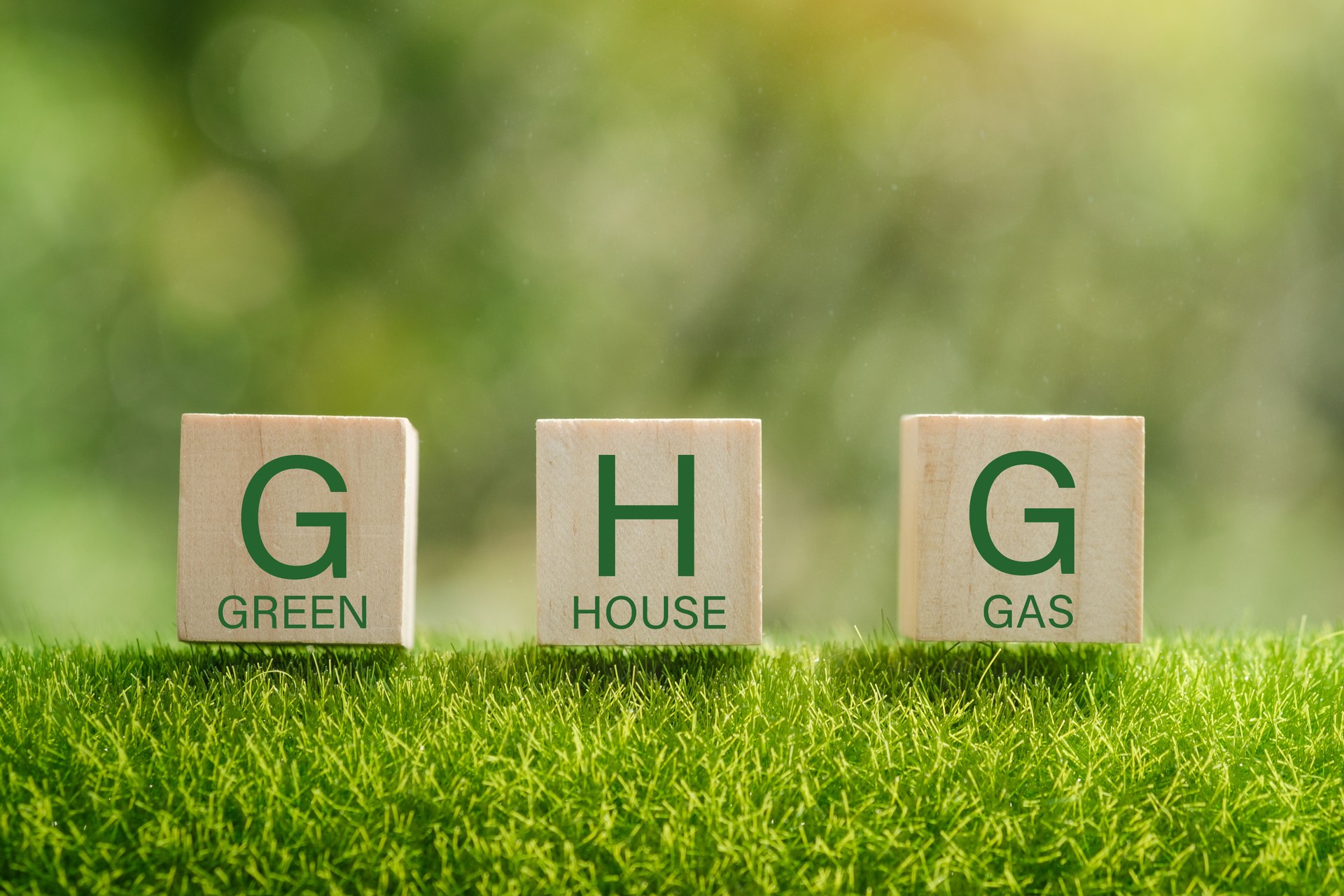 Business and GHG concept. Copy space. Greenhouse gas symbol. Concept words 'GHG, greenhouse gas' on cubes and blocks on a beautiful green background.